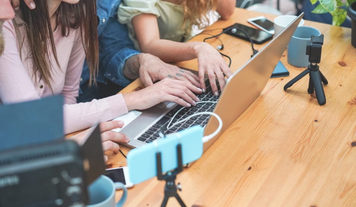 Young people streaming online using laptop, leds, smartphone and action cameras - Social network, vlogging and tech concept - Focus on left girl hand